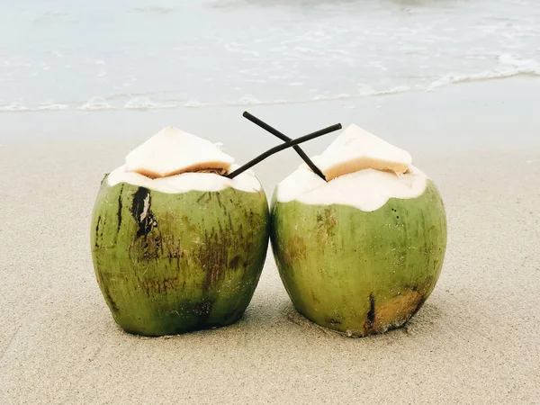 Two coconuts with a tube stand on the beach, Paradise island, Thailand