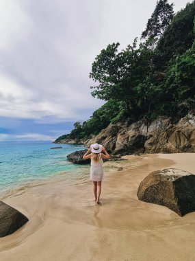 Mavi denizin kıyısında şapkalı ve gözlüklü çekici bir kız tatilin tadını çıkarıyor ve Tayland 'da kayalarla dolu vahşi bir sahilde seyahat ediyor.