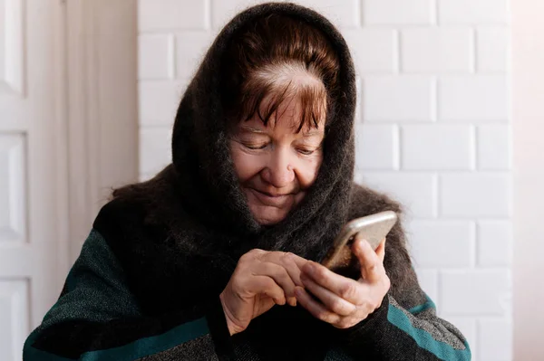 An elderly grandmother holds a mobile phone for the first time during the quarantine period of the coronavirus pandemic