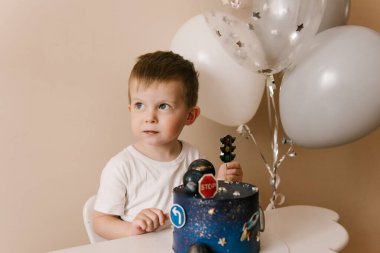 Sevimli çocuk doğum gününü kutluyor ve nefis bir pasta yiyor. Balonlu bir çocuğun fotoğrafı.