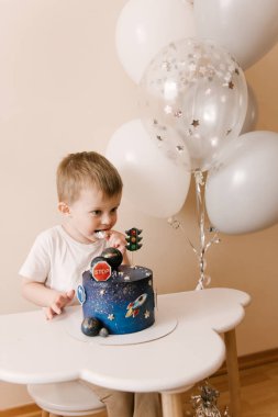 Sevimli çocuk doğum gününü kutluyor ve nefis bir pasta yiyor. Balonlu bir çocuğun fotoğrafı.
