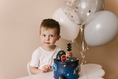 Sevimli çocuk doğum gününü kutluyor ve nefis bir pasta yiyor. Balonlu bir çocuğun fotoğrafı.