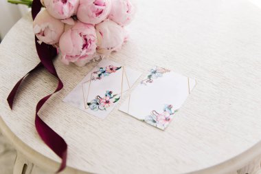 Güzel bir buket pembe şakayığın yanında boş yer olan düğün davetiyeleri.