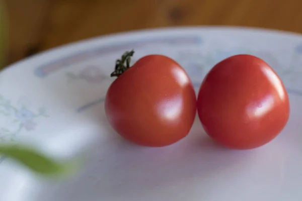 Два крошечных красных помидора красиво лежат на тарелке. Крупный план. D — стоковое фото
