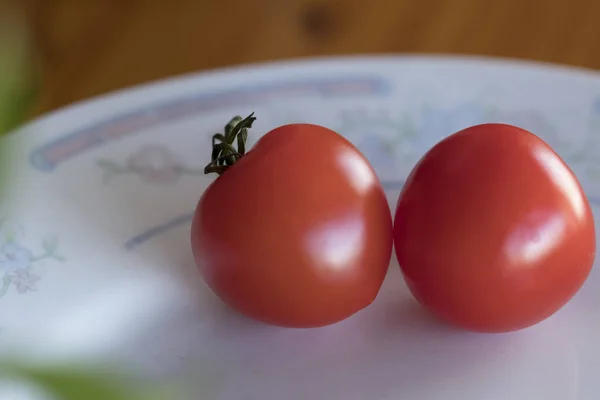 Два крошечных красных помидора красиво лежат на тарелке. Крупный план. D — стоковое фото