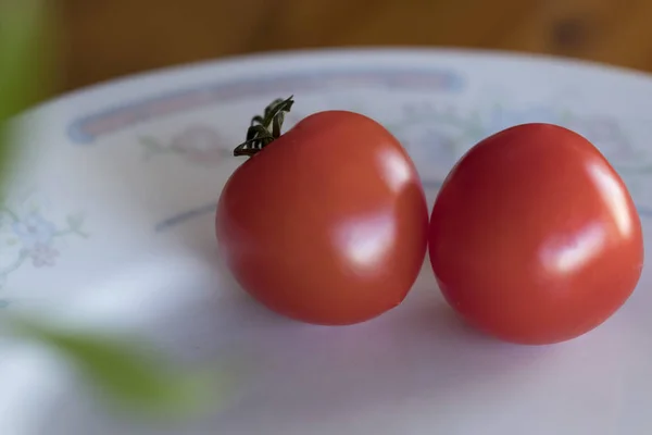 Dos pequeños tomates rojos bellamente colocados en un plato. Primer plano. D) — Foto de Stock