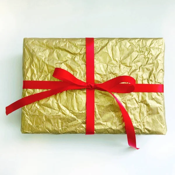 Χρυσό χριστουγεννιάτικο δώρο με κόκκινη κορδέλα σε λευκό φόντο — Φωτογραφία Αρχείου
