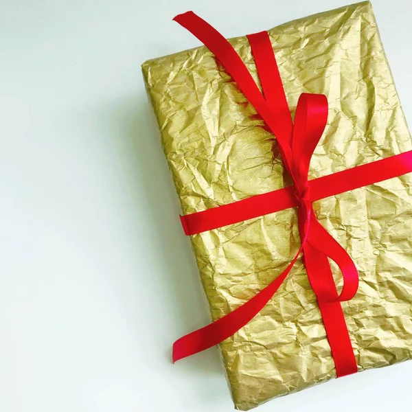 Beyaz arkaplanda kırmızı kurdeleli altın noel hediyesi — Stok fotoğraf