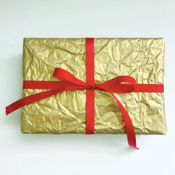 하얀 배경에 빨간 리본 이 있는 황금색 크리스마스 선물 — 스톡 사진