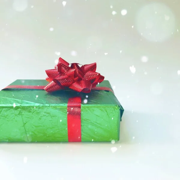 Zelená vánoční dárek s červenou mašlí na bílém pozadí — Stock fotografie