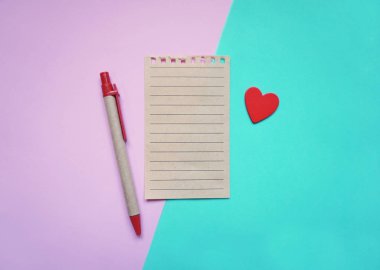 Sevgililer Günü geçmişi. Boş boş defter, parlak bir arkaplan üzerinde kalem ve kalp, üst görünüm. Metin için boş alan