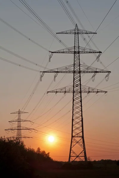 Solnedgången bakom en power pyloner — Stockfoto