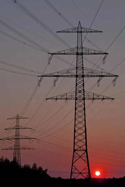 Solnedgången bakom en power pyloner — Stockfoto