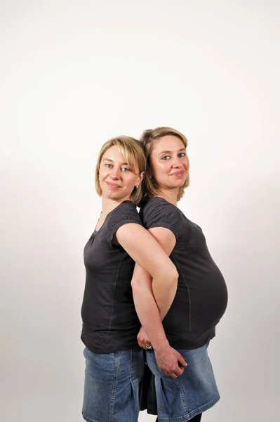 Zwillingsschwestern Von Denen Eine Schwanger Ist Rücken Rücken Stehend — Stockfoto
