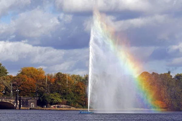 Alster fountain water fountain with a rainbow on the Inner Alster lake in the center of the Hanseatic city of Hamburg, Germany, Europe