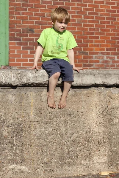 Młody Chłopiec Siedzi Ścianie — Zdjęcie stockowe
