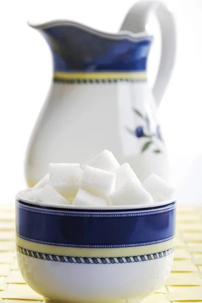 White sugar cubes in a sugar bowl, in front of a coffee pot