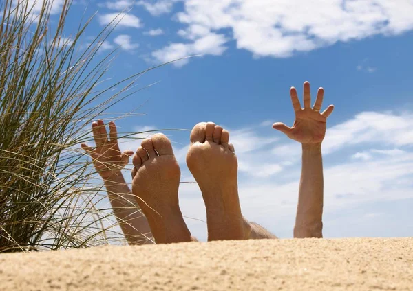 Men's feet in a sand dune by the sea