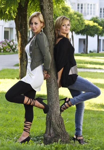 Dwie Młode Kobiety Opierające Się Drzewo — Zdjęcie stockowe