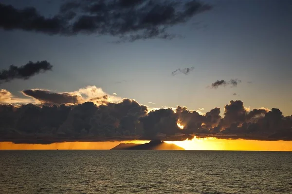 シルエット島の背後に夕日 — ストック写真