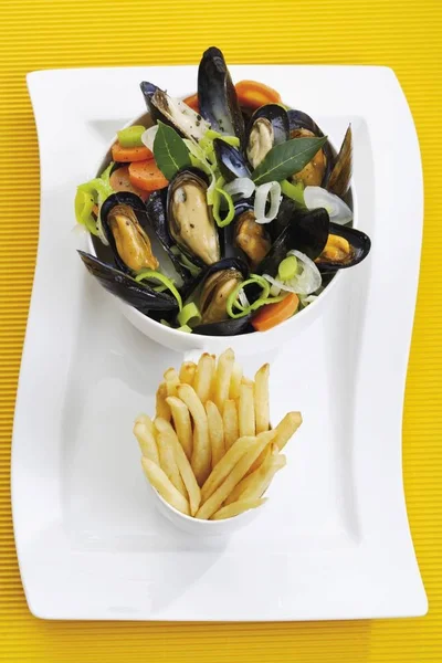 Mussels, rheinische art, with onions in a spicy sauce, in a porcelain dish with chips