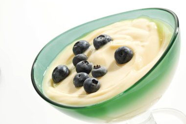 Vanilla pudding with blueberries and raspberries in a glass bowl clipart