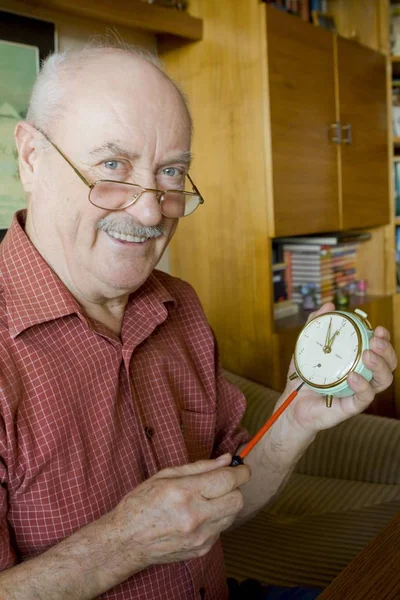 Pensioner Repairing Alarm Clock — Stock Photo, Image