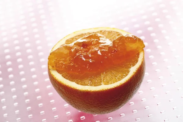 Orange marmalade spread on a half of an orange