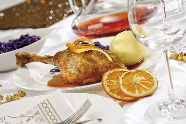 Goose-leg, red cabbage, potato dumpling on a festively decorated table