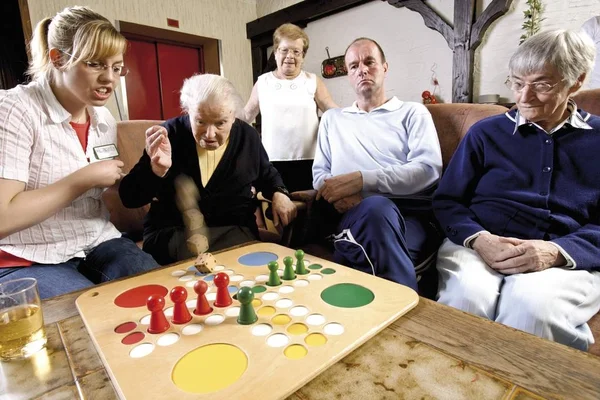 Sygeplejersker Beboere Alderdomshjem Eller Plejehjem Spiller Brætspil Eftermiddagen - Stock-foto