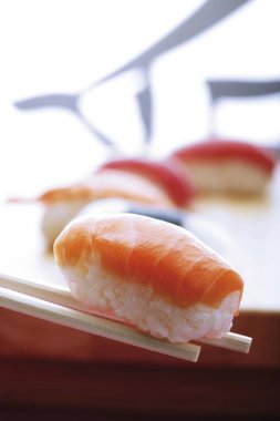 Chopsticks holding nigiri sushi and salmon clipart