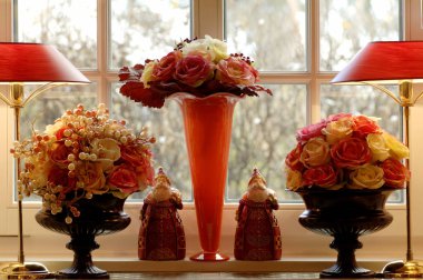Three flower vases with rose blossoms in front of a window clipart