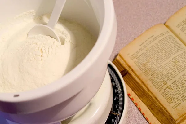 Cookery book and bowl of flour on scales