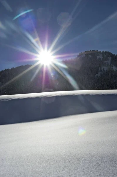 Zonnestralen achter berg in de winter — Stockfoto