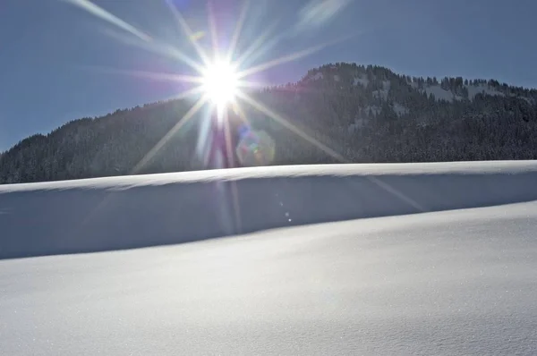 Zonnestralen achter berg in de winter — Stockfoto