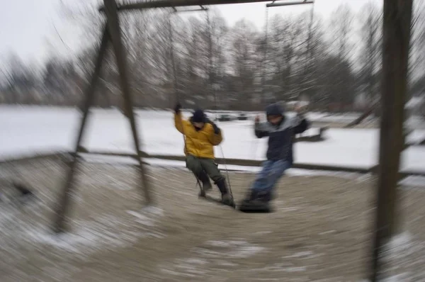 两个男孩在操场上荡秋千冬天 — 图库照片