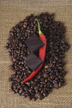 Red pepper and chocolate on coffee beans clipart