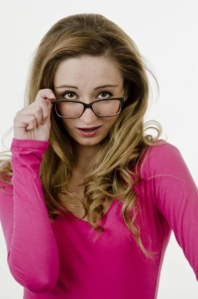 Genç Bir Kadın Yaşında Gözlüklerinin Kenarından Bakıyor — Stok fotoğraf