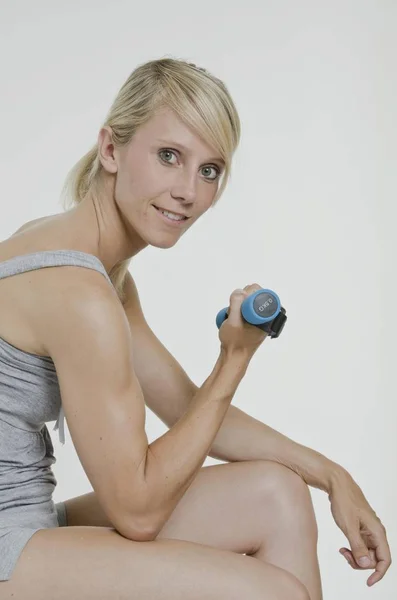 Oturma Onun Sağ Elinde Küçük Bir Dumbbell Tutarak Genç Kadın — Stok fotoğraf