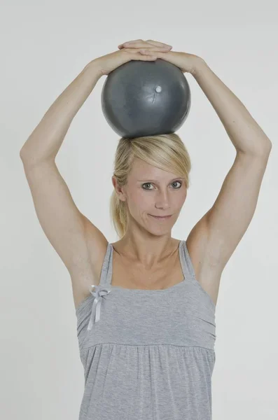 Egzersiz Topu Iki Eliyle Başını Tutan Genç Kadın — Stok fotoğraf