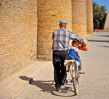 Onun dedesi bir bisiklet üzerinde oturan küçük kız