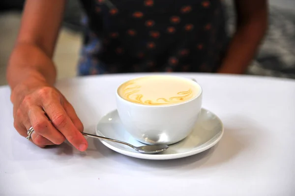 Una tazza di cappuccino e mano di donna — Foto Stock