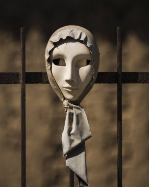 SAN SPERate, SARDINIA, İTALYA - 30 Eylül 2019: Beyaz kadın maskesi başörtüsüne sarılı olarak demir ızgarada aç bir şekilde caddede sergileniyor.