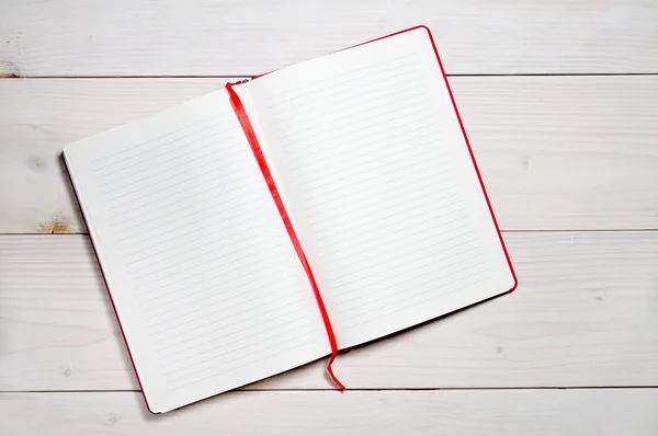 Beyaz ahşap arka plandaki günlük notlar için kırmızı defter