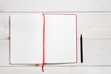 Beyaz ahşap arka plandaki günlük notlar için kırmızı defter