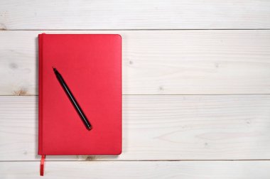 Beyaz ahşap arka plandaki günlük notlar için kırmızı defter