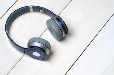 Beyaz ahşap arka planda müzik dinlemek için mavi ve gümüş kulaklıklar.