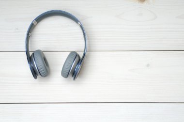 Beyaz ahşap arka planda müzik dinlemek için mavi ve gümüş kulaklıklar.