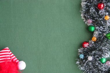 Yeni yıl tinsel, garland, toplar ve yeşil bir arka plan üzerinde kırmızı bere.