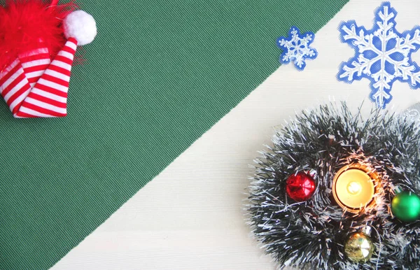 Πρωτοχρονιάτικα στολίδια, μπάλες, ένα καίγοντας κερί, ένα κόκκινο σκουφάκι, νιφάδες χιονιού σε πράσινο φόντο. — Φωτογραφία Αρχείου